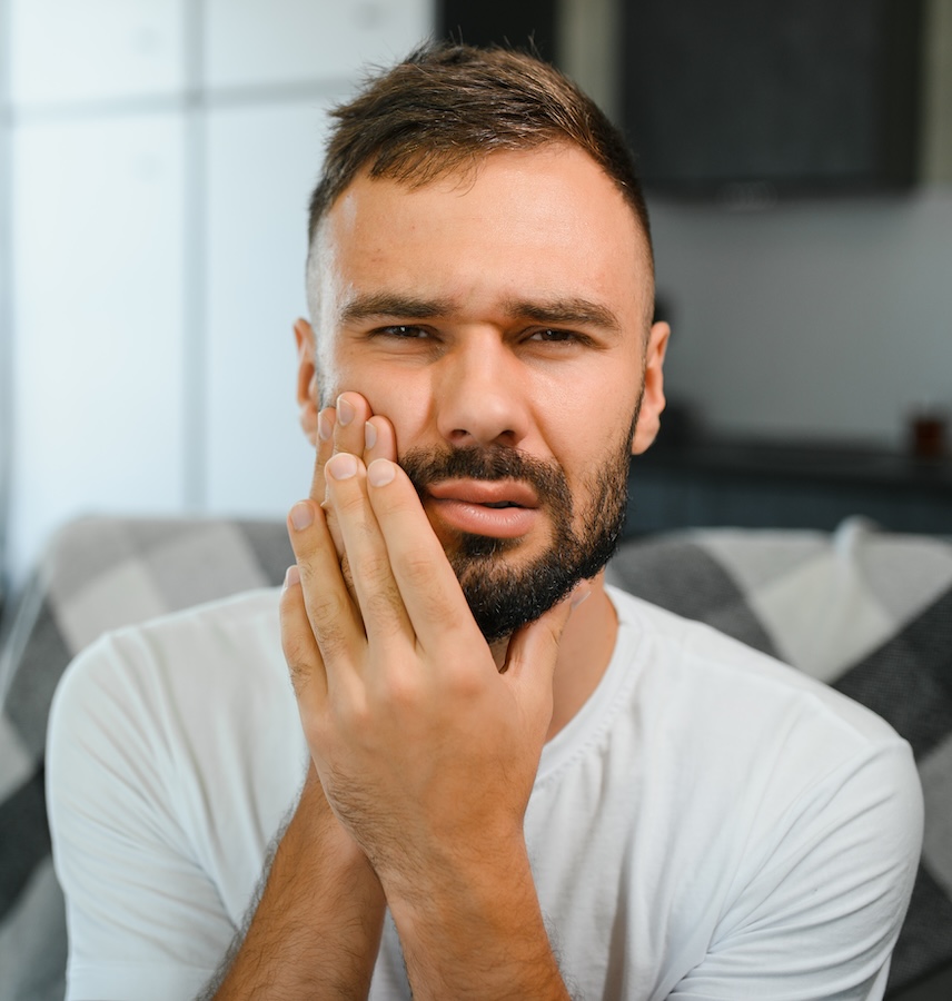 Mann hält sein Gesicht vor Schmerz – mögliches Symptom einer Parodontitis, behandelt in der Praxis Dr. Michaela Strumpski, Halle.