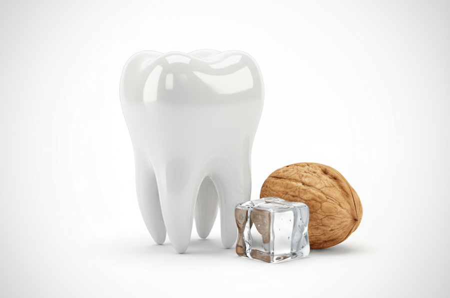 Symbolbild Zahn neben Eiswürfel und Walnuss – Hinweis auf Risiken für Zahntrauma, Praxis für Zahnerhaltung Halle.